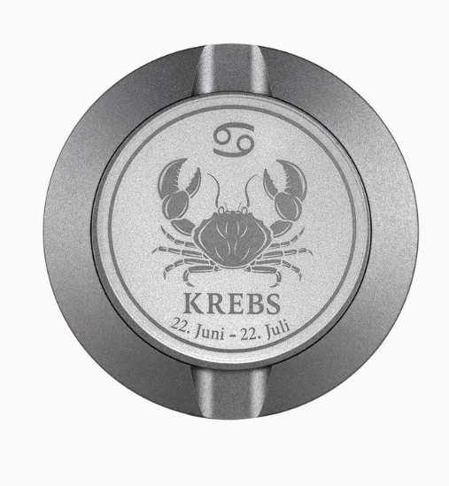 Dreiteilige Snusdose in Grau mit eingraviertem Sternzeichen - Motiv Krebs auf dem Deckel, stilvoll arrangiert auf einem dunklen Hintergrund.