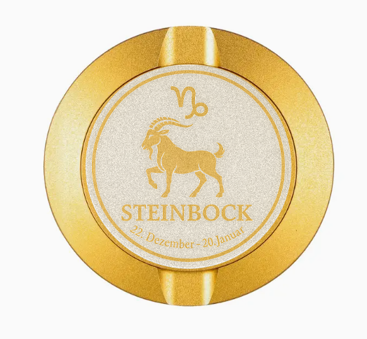 Dreiteilige Snusdose in Gold mit eingraviertem Sternzeichen - Motiv Steinbock auf dem Deckel, stilvoll arrangiert auf einem dunklen Hintergrund.