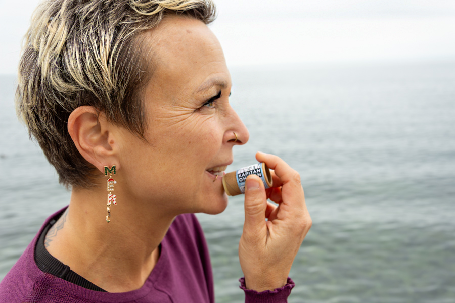 Person trägt Kapitän Olsens Schnutenschmiere Lippenpomade auf, Anwendung des Pflegeprodukts.