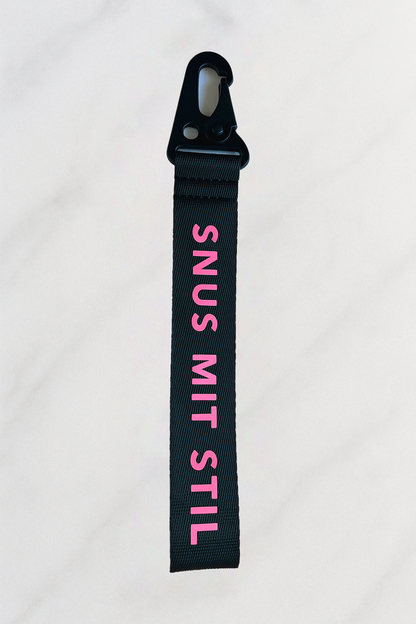Schwarzer Snus-Schlüsselanhänger mit pinkem Aufdruck "Snus mit Stil" und Metallkarabiner