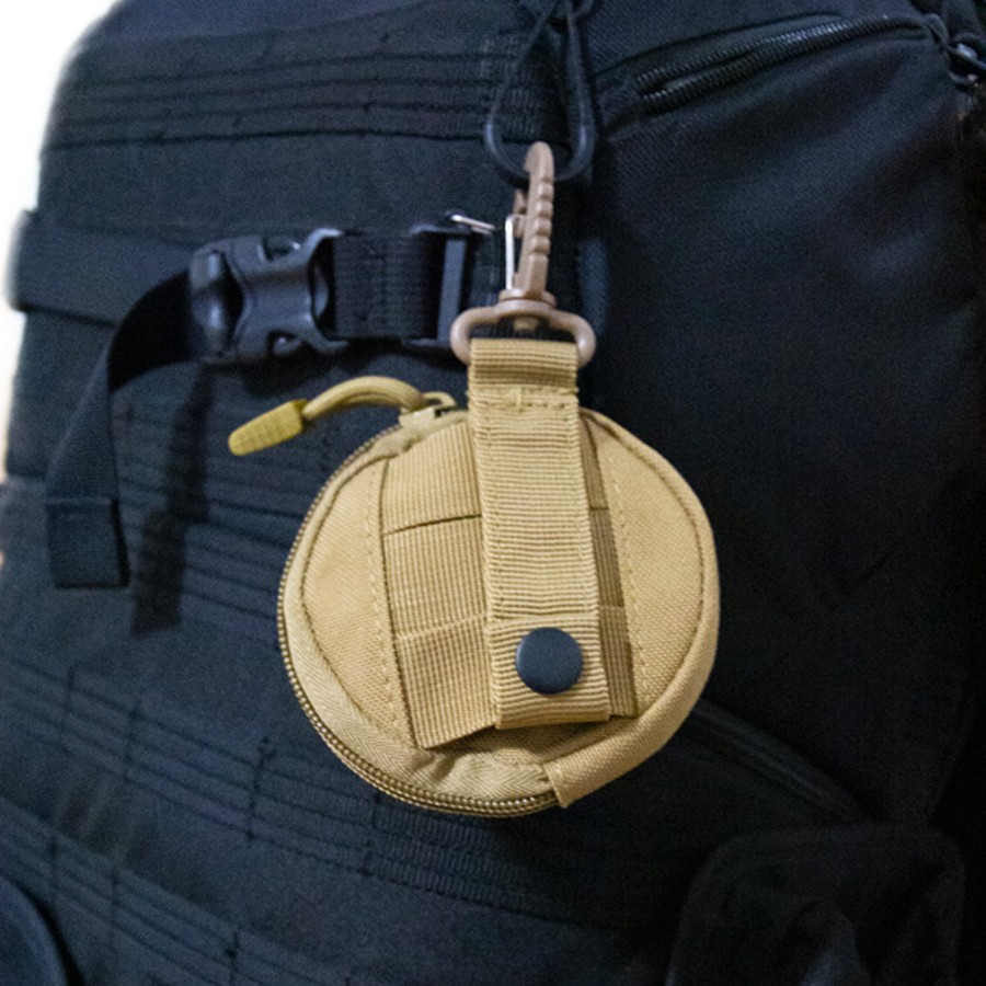Hellbrauner SnusTag Anhänger im Einsatz, befestigt an Rucksack, Outdoor-Accessoire.